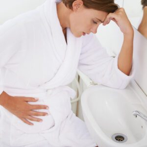 A pregnant woman struggling with morning sickness in the bathroom.