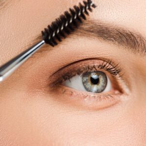 cropped view of woman holding eyebrow brush near eyebrow