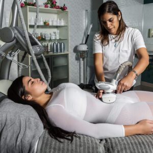Side view of relaxing woman enjoying massage with special equipment from professional master in center
