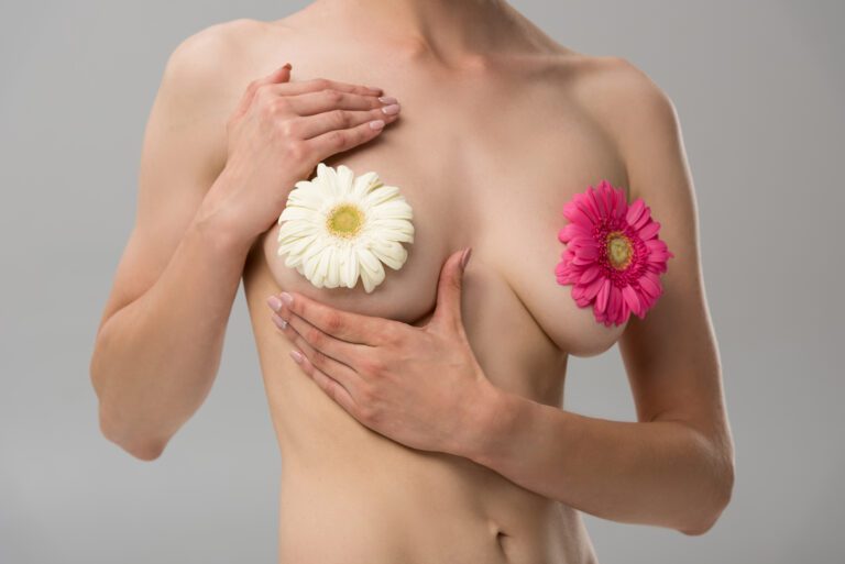 partial view of naked young woman with flowers isolated on grey