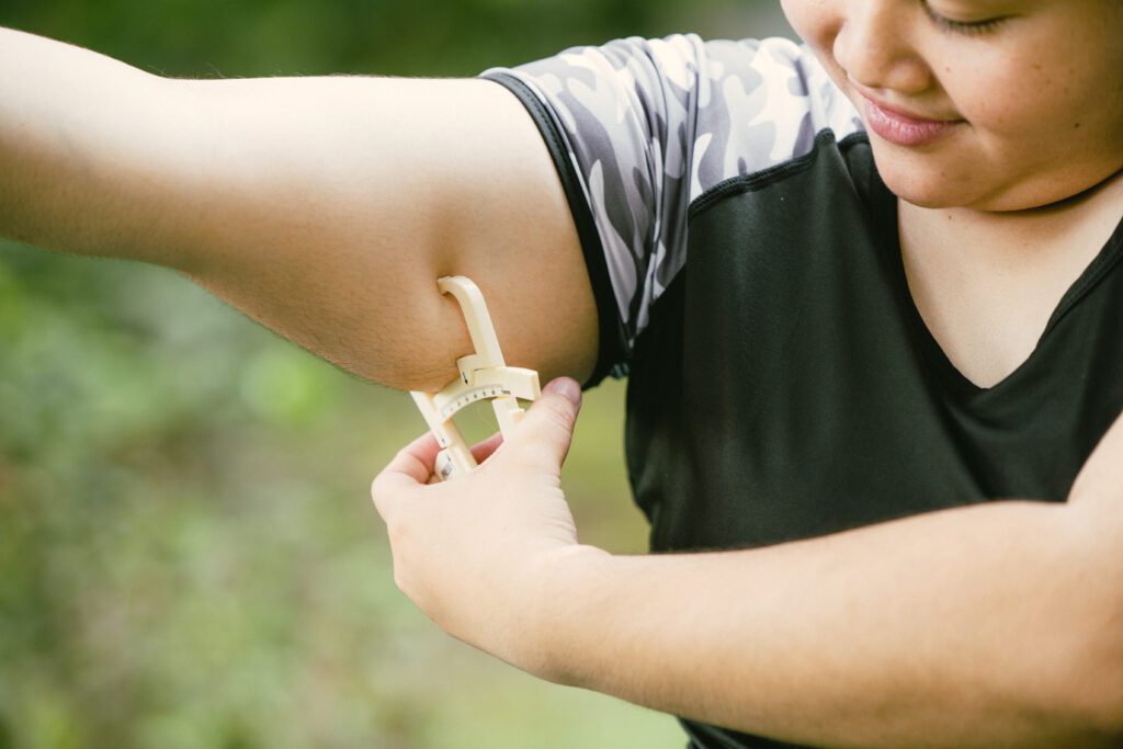 Skinfold calipers measure fat thickness under arm of young woman