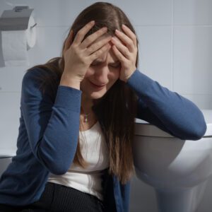 Young upset woman sitting in toilet and crying. Victim of home violence. Female depression