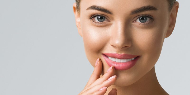 Beauty woman skin care beautiful female hand touching face cosmetic girl model over blue background